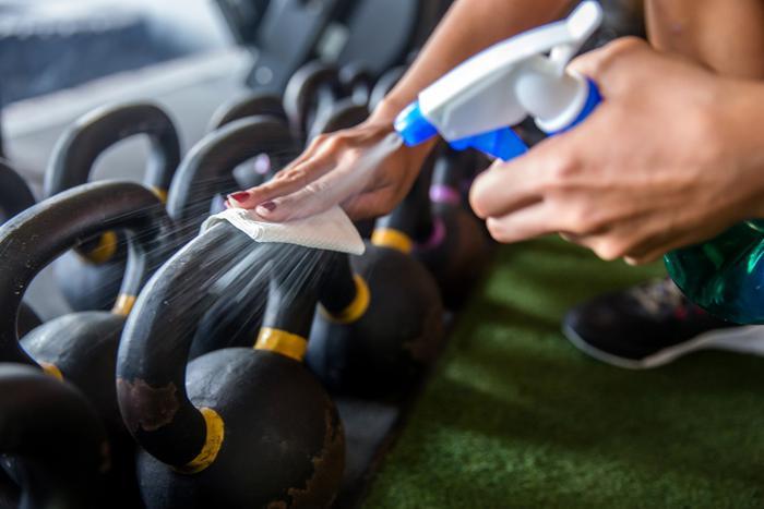 women cleaning gym equipment